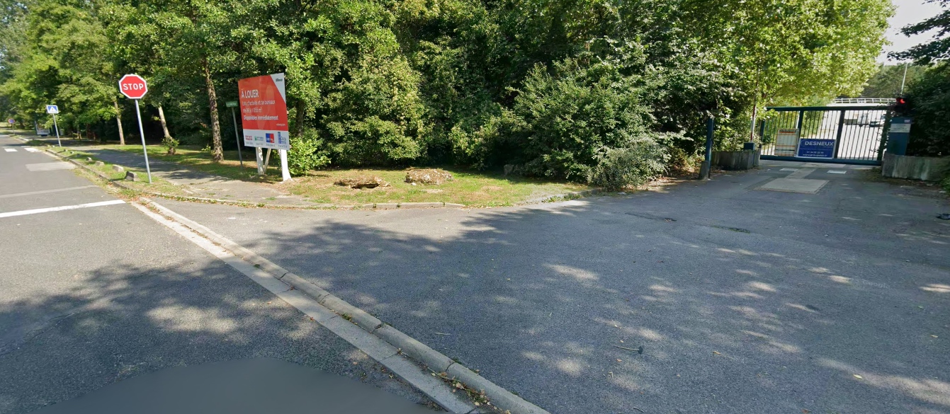 Vue d'angle de la rue avec le panneau STOP rouge et le portail KB Traiteur visible à droite